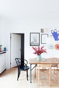 a dining room table with chairs and pictures on the wall