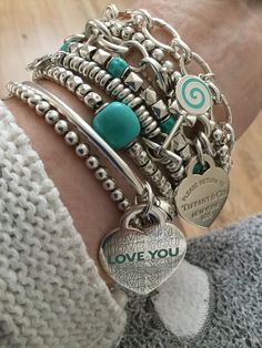 a woman's arm with bracelets and charms on it, which says love you