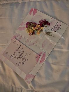 two greeting cards with flowers are on a bed
