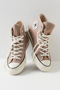 a pair of beige sneakers with white laces