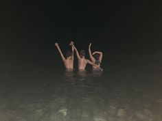 two people in the water with their hands up and one person holding his head above them