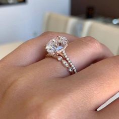 a woman's hand with a diamond ring on top of her finger and the other hand holding an engagement ring