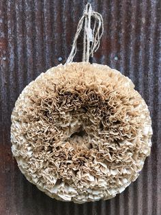 a close up of a doughnut hanging from a string on a metal wall with rusted paint