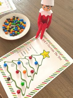 an elf is sitting on top of a paper with candy in the shape of a christmas tree