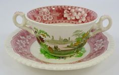 an antique tea cup and saucer with pink flowers on the rim, sitting on a white background