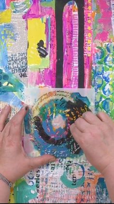 two hands are working on an art project with colorful paper and collaged images