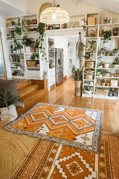 a living room filled with lots of furniture and plants on top of a hard wood floor