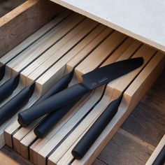four knives sitting on top of a wooden table next to each other in a drawer