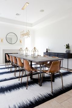 a dining room table with six chairs and a rug on the floor in front of it
