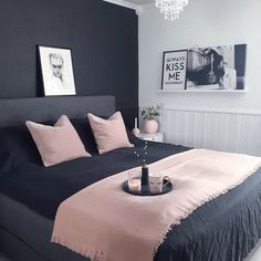 a black and pink bedroom with chandelier above the bed, artwork on the wall