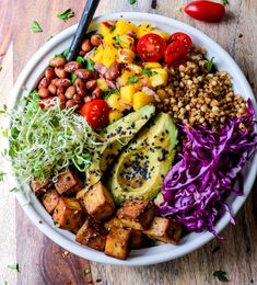 a white bowl filled with lots of different types of food on top of a wooden table