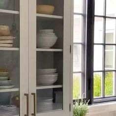 a kitchen cabinet with glass doors and dishes in it