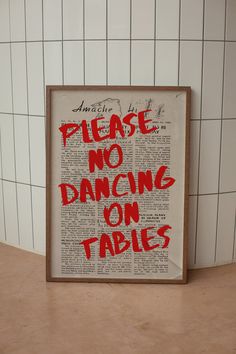 there is a sign that says please no dancing on tables in front of a tiled wall