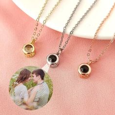three different necklaces on a plate with a photo in the middle and one has an image of two people holding each other