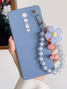 a woman holding up a blue phone case with flowers on it