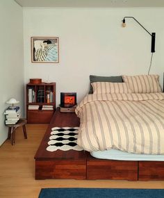 a bed sitting on top of a wooden platform next to a night stand and lamp