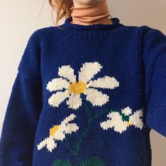 a woman wearing a blue sweater with white flowers on it