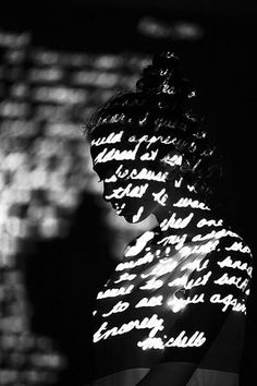 black and white photograph of a woman's face with words projected on her shirt