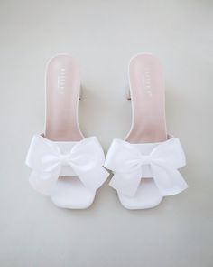 a pair of white shoes with a large bow on the front and bottom part of them