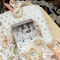 an altered photo is sitting on top of doily with lace, buttons and other items