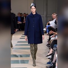 a model walks down the runway in a blue coat and leopard print leggings