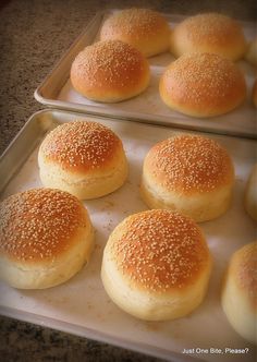 six buns with sesame sprinkled on them sitting in a baking pan next to each other