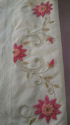 an embroidered table runner with pink flowers on white linens and gold trimmings
