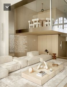 a living room filled with white furniture next to a tall glass wall above it's windows