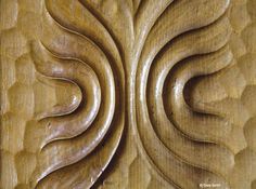 an intricate wood carving pattern on the side of a wooden paneled wall with wavy lines