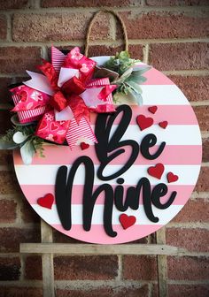 a sign that says be mine hanging on the side of a brick wall with hearts