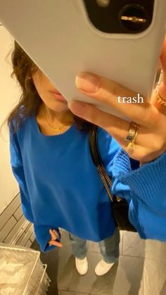 a woman taking a selfie with her cell phone in front of her face while wearing a blue sweater