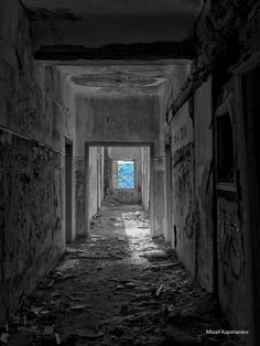 an empty hallway with graffiti all over the walls and floor, leading to a window