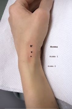 a woman's arm with two small hearts tattooed on the left side of her wrist