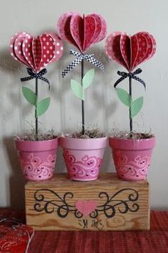 three potted plants with hearts in them on top of a wooden box filled with grass
