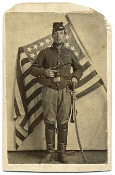 an old black and white photo of a man in uniform with a flag behind him