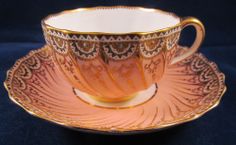 an antique tea cup and saucer with gold trimmings on the rim, sitting on a blue background