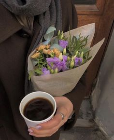 a woman is holding a cup of coffee and bouquet of flowers in her left hand