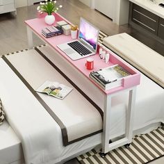 a laptop computer sitting on top of a pink table next to a white bed in a room