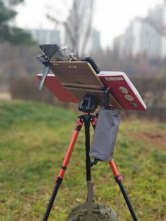 a tripod with a laptop and camera on it sitting in the middle of a field