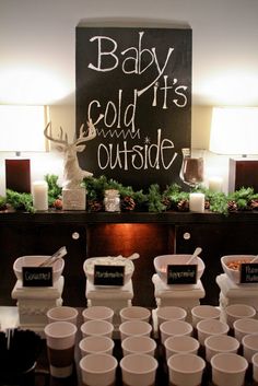 the baby it's cold outside sign is displayed in front of cups and candles