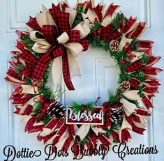 a red and white christmas wreath with pine cones, evergreens and plaid ribbon hanging on the front door