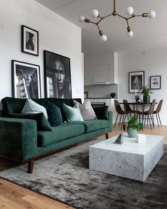 a living room with green couches and pictures on the wall above it's coffee table