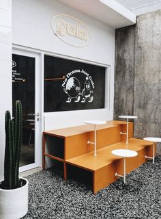 an orange bench sitting in front of a window next to a cactus