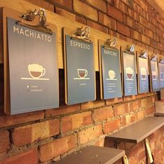 there are many menus on the wall next to each other in front of a brick wall