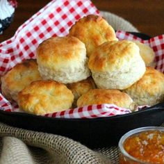 some biscuits are in a black pan on a red and white checkered cloth