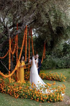 the bride and groom are standing in front of an orange flowered garden with flowers