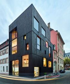 the building has many windows and is made out of black wood, with multiple levels