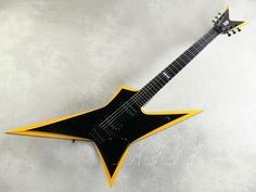 a black and yellow guitar with an orange star on the top, sitting on a white surface