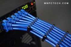 several blue cables connected to the back of a computer server in front of a black background