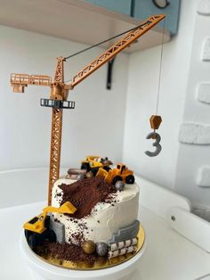 there is a cake with construction trucks on the top and dirt in the bottom tier